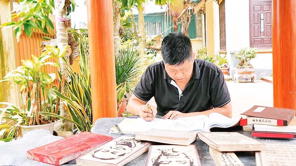 Nghệ nhân trẻ Nguyễn Công Đạt say mê với công việc khắc mộc bản. 