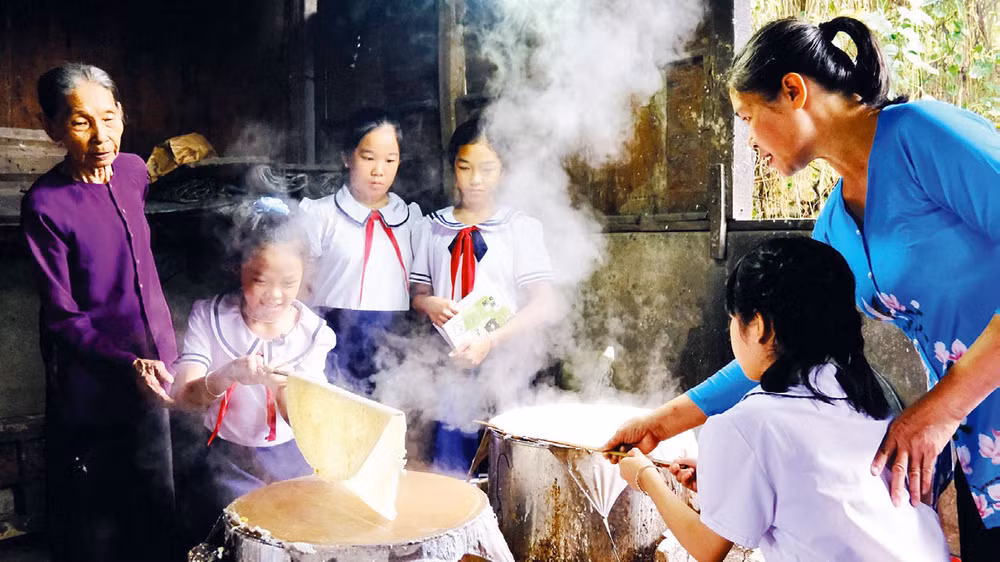 Nghệ nhân Đặng Thị Túy Phong (ngoài cùng bên trái) và con gái hướng dẫn học sinh trải nghiệm tráng bánh.