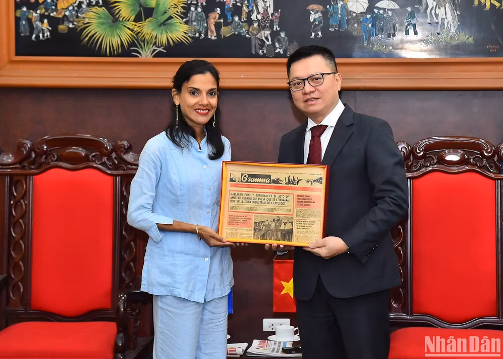 Tổng Biên tập Báo Nhân Dân Lê Quốc Minh nhận quà lưu niệm của Phó Tổng Biên tập Báo Granma Arlin Alberty Loforte. (Ảnh: THỦY NGUYÊN)