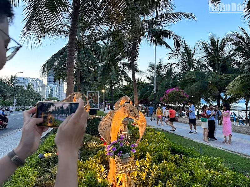 Một du khách ghi lại hình Cá dạo phố Biển trên Đường hoa biển Đà Nẵng chiều 5/7. (Ảnh: ANH ĐÀO)