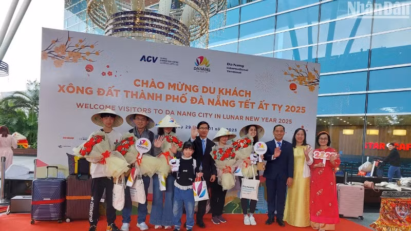 Những hành khách quốc tế đến Đà Nẵng bằng đường hàng không đón nhận quà và chụp ảnh lưu niệm cùng đại diện Sở Du lịch thành phố Đà Nẵng. (Ảnh: ANH ĐÀO)