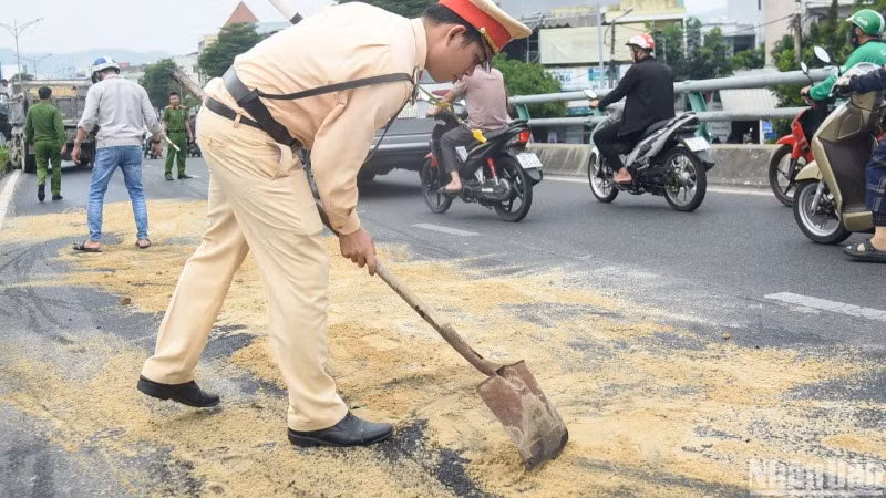 Lực lượng chức năng rải cát xuống khu vực dầu nhớt của xe tải bị nạn đổ loang, để hạn chế các phương tiện trơn trượt gây nguy hiểm. (Ảnh: ANH ĐÀO)