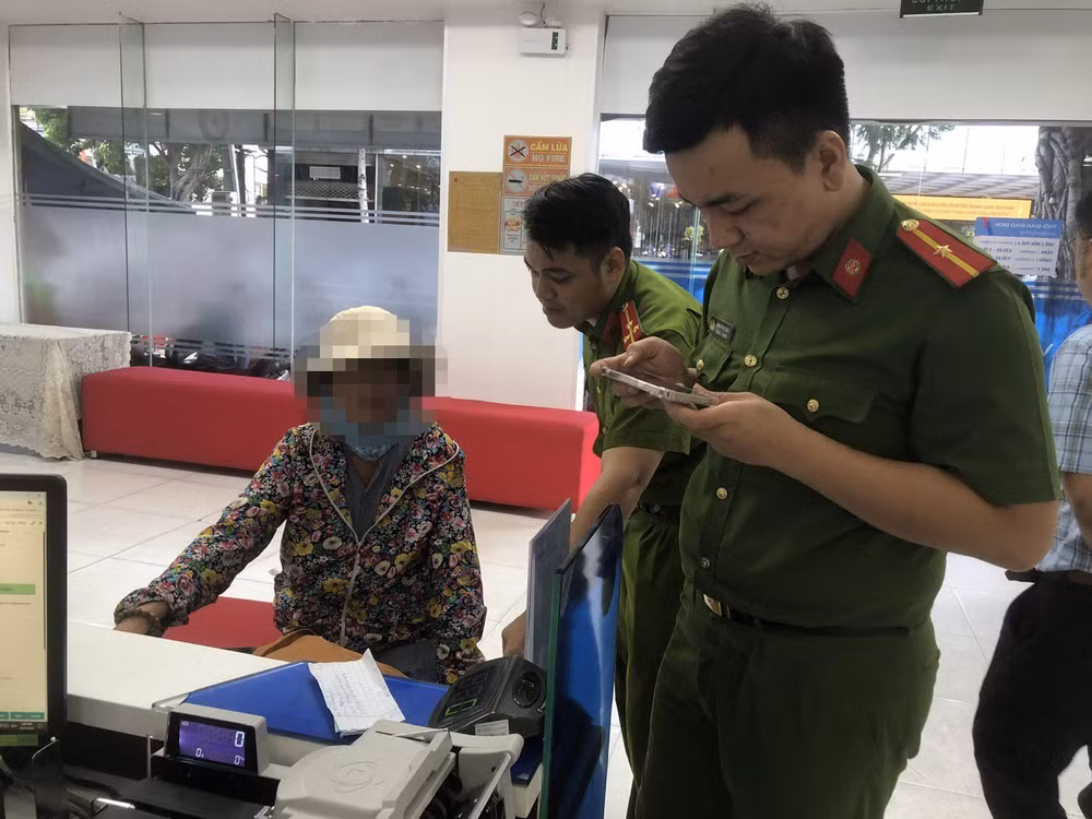 Lực lượng chức năng hướng dẫn bà N chuyển gửi tiết kiệm số tiền 300 triệu đồng cho ngân hàng. (Ảnh: Công an cung cấp)