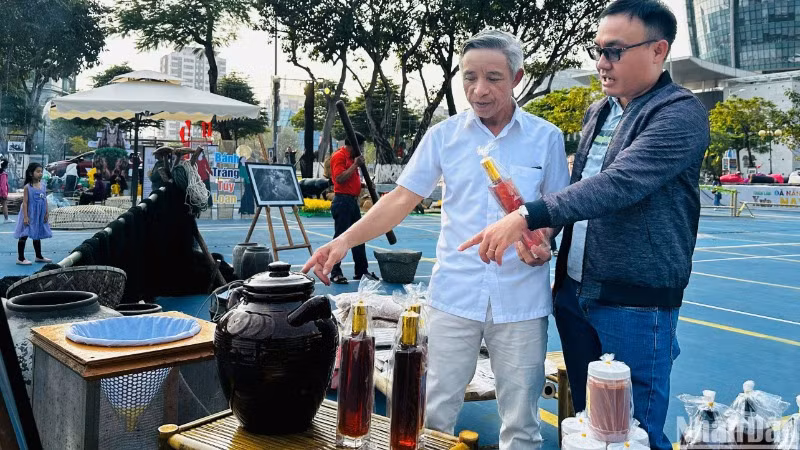 Ông Huỳnh Văn Mười (59 tuổi, trú phường Mân Thái, quận Sơn Trà, Đà Nẵng) đang giới thiệu về văn hóa biển và nghề làm nước mắm nhĩ của ngư dân làng biển Mân Thái với du khách tại triển lãm "Đà Nẵng - Xưa và Nay". (Ảnh: ANH ĐÀO)