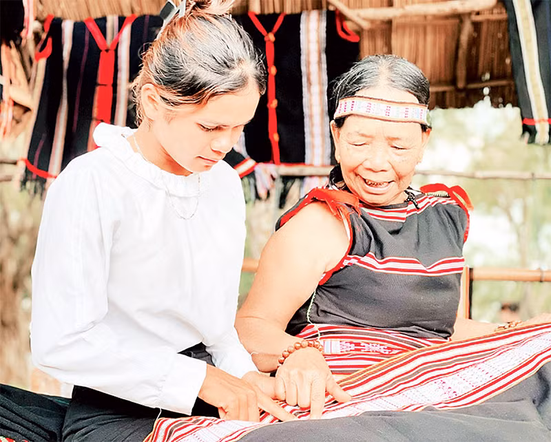 Nghệ nhân truyền dạy cách dệt hoa văn trên thổ cẩm truyền thống cho thế hệ trẻ.