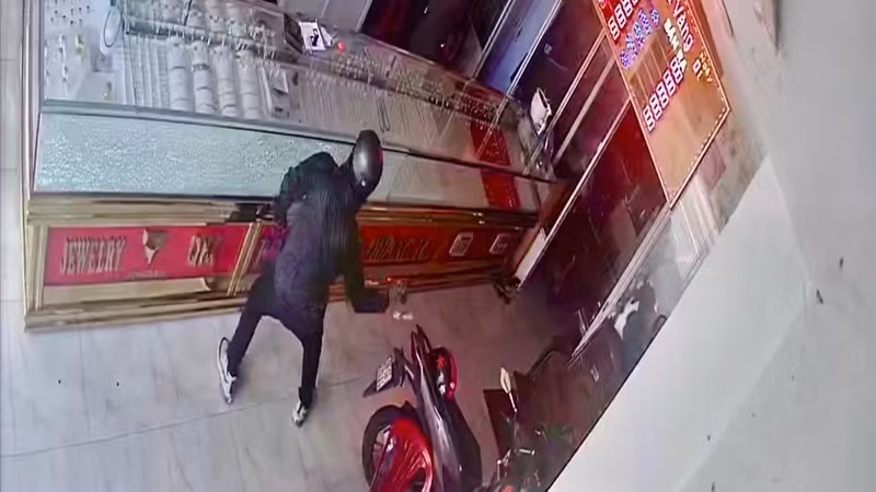 Một trong hai đối tượng dùng búa đập tủ kính cướp tài sản. (Ảnh cắt từ clip Công an cung cấp) Một trong hai đối tượng dùng búa đập tủ kính cướp tài sản. (Ảnh cắt từ clip Công an cung cấp)