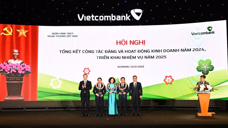 Ban lãnh đạo Vietcombank trao biểu trưng và tặng hoa vinh danh cho đại diện 3 Đơn vị đặc biệt xuất sắc trong năm 2024: Chi nhánh Sở Giao dịch (thứ 4 từ trái sang), Chi nhánh Thành Công (thứ 3 từ trái sang) và Chi nhánh Nam Sài Gòn (thứ 2 từ trái sang). Ban lãnh đạo Vietcombank trao biểu trưng và tặng hoa vinh danh cho đại diện 3 Đơn vị đặc biệt xuất sắc trong năm 2024: Chi nhánh Sở Giao dịch (thứ 4 từ trái sang), Chi nhánh Thành Công (thứ 3 từ trái sang) và Chi nhánh Nam Sài Gòn (thứ 2 từ trái sang).