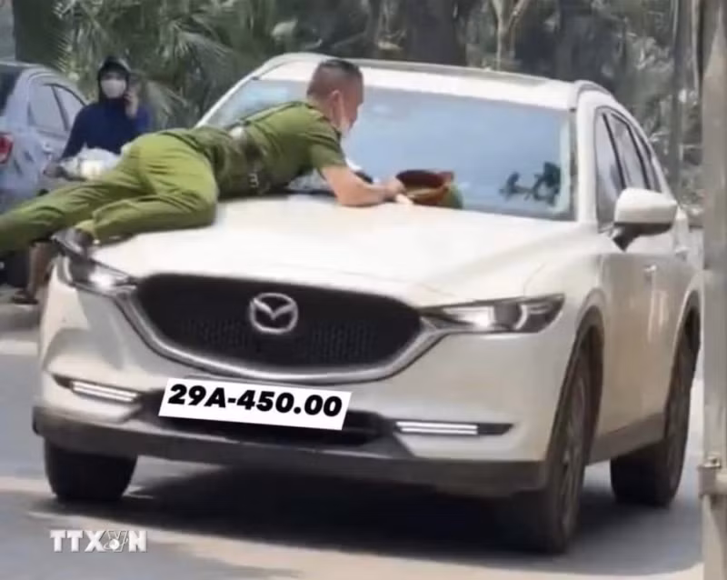 Hình ảnh vụ việc hất văng chiến sĩ Công an lên nắp ca-pô xe ô-tô. (Ảnh: TTXVN phát)