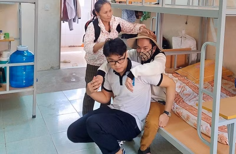 Nguyễn Văn Thắm được bạn sinh viên người Lào Sevaphom Chanthakone cõng lên giảng đường. Nguyễn Văn Thắm được bạn sinh viên người Lào Sevaphom Chanthakone cõng lên giảng đường.