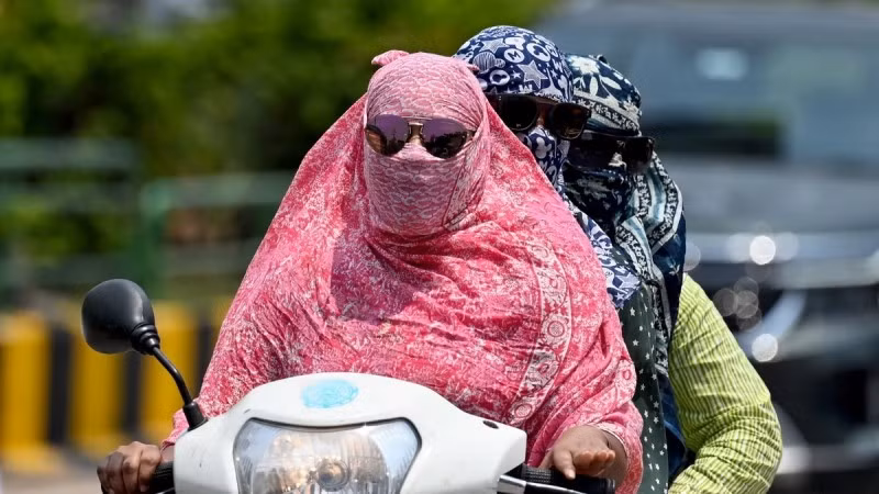 Người dân trùm kín tránh nắng nóng khi di chuyển tại Raipur, Ấn Độ. (Ảnh: AFP/TTXVN)
