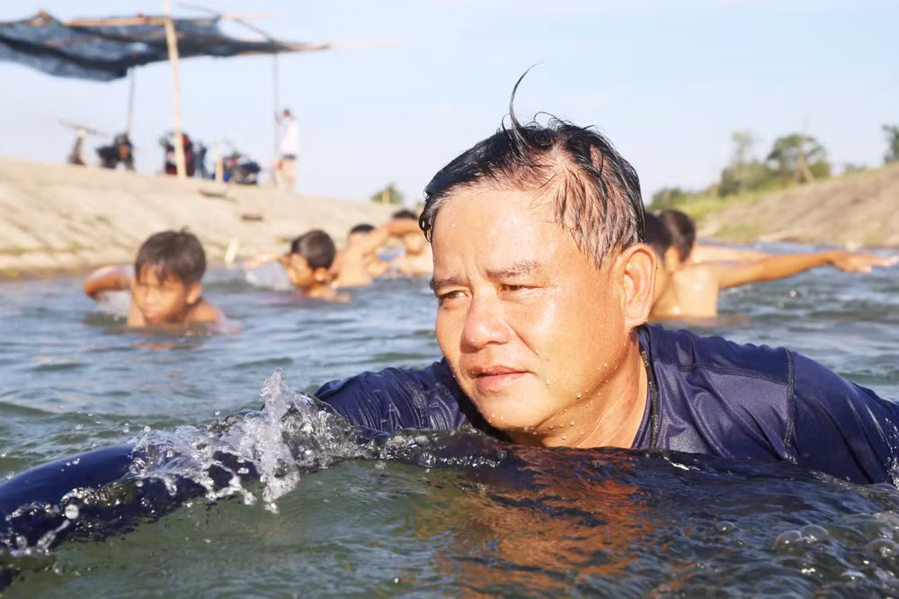 Thầy Nguyễn Viết Tước dầm mình giữa nước để dạy bơi cho học sinh.