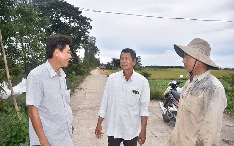 Ông Lương Văn Tạo (ở giữa), Bí thư Chi bộ, Trưởng ấp Sóc Cung tuyên truyền cho người dân về ý nghĩa của việc hiến đất làm đường giao thông nông thôn.