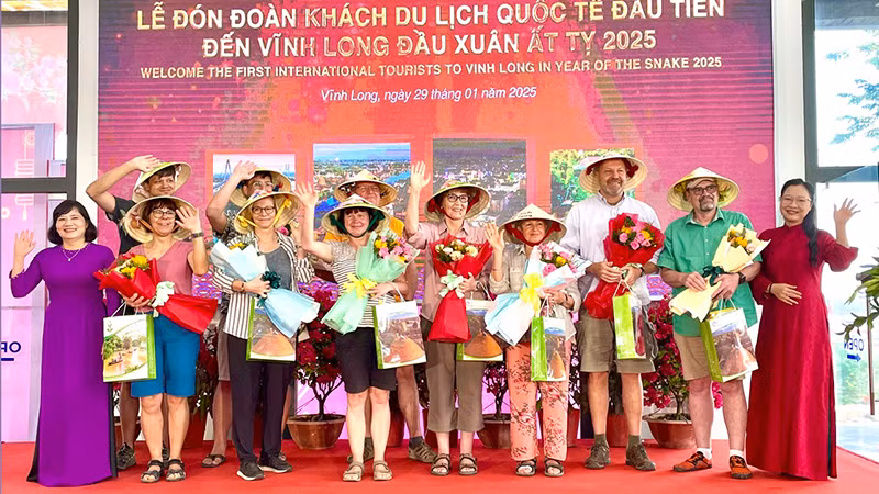 Lãnh đạo tỉnh Vĩnh Long tặng quà và hoa cho khách du lịch quốc tế đầu tiên. 