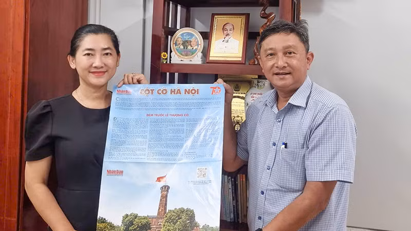 Phó Giám đốc Sở Giáo dục và Đào tạo tỉnh Vĩnh Long Nguyễn Thị Ngọc Bích phấn khởi tiếp nhận phụ san Báo Nhân dân về Cột cờ Hà Nội. 