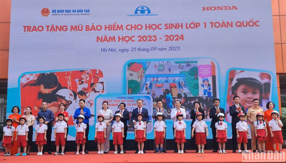 Đại diện Ban tổ chức trao tặng mũ bảo hiểm cho các em học sinh Trường tiểu học Phú Đô (Hà Nội).