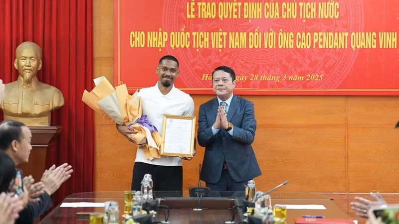 Đại diện Sở Tư pháp thành phố Hà Nội trao quyết định nhập quốc tịch Việt Nam cho cầu thủ Cao Pendant Quang Vinh. (Ảnh: PHAN THẠCH).