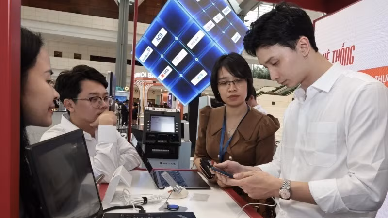 Hướng dẫn khách hàng sử dụng ngân hàng online tại Diễn đàn Chuyển đổi số ngành Ngân hàng năm 2024. (Ảnh TTXVN)