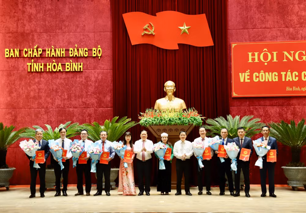 Bí thư Tỉnh ủy Hòa Bình Nguyễn Phi Long (thứ 6 từ trái sang) và Chủ tịch Ủy ban nhân dân tỉnh Bùi Văn Khánh (thứ 5 từ phải sang) trao Quyết định và tặng hoa các đồng chí được luân chuyển, bổ nhiệm tại hội nghị.
