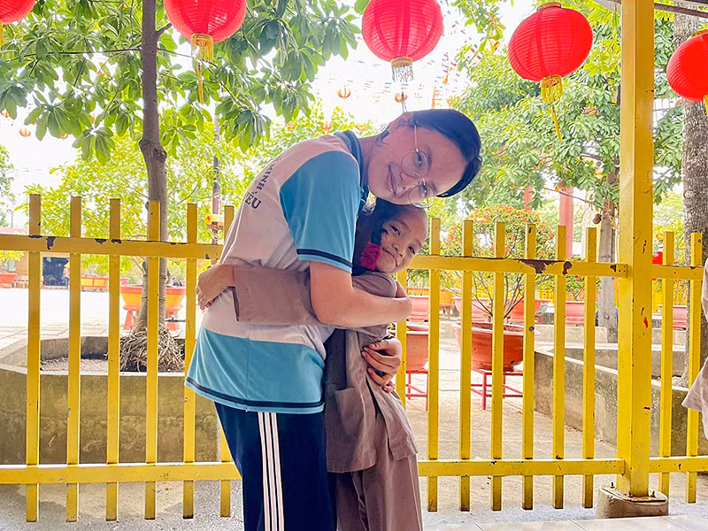 Minh Anh chụp ảnh lưu niệm với 1 em nhỏ trong chuyến thiện nguyện tại chùa Từ Hạnh (quận Bình Tân) cùng bạn bè Trường Phổ thông Năng khiếu. Ảnh: Nhân vật cung cấp