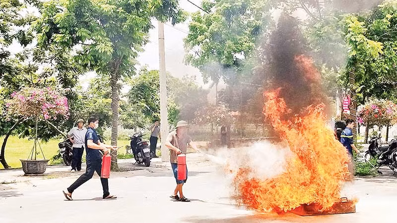 Người dân xã Yên Mỹ, huyện Thanh Trì thực hành sử dụng bình chữa cháy để dập lửa. (Ảnh NGUYỄN QUÂN)