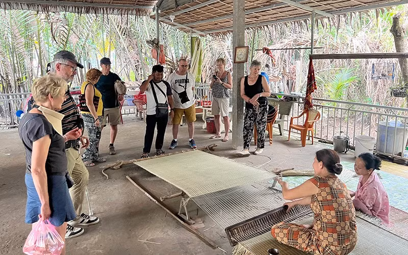 Khách du lịch nước ngoài theo dõi công đoạn dệt chiếu tại xã Nhơn Thạnh (thành phố Bến Tre, tỉnh Bến Tre). Khách du lịch nước ngoài theo dõi công đoạn dệt chiếu tại xã Nhơn Thạnh (thành phố Bến Tre, tỉnh Bến Tre).