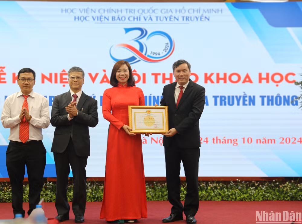 Giáo sư, Tiến sĩ Lê Văn Lợi, Phó Giám đốc Học Viện Chính trị Quốc gia Hồ Chí Minh trao bằng khen của Giám đốc Học viện Chính trị Quốc gia Hồ Chí Minh cho Tạp chí Lý luận chính trị và Truyền thông. (Ảnh: HẢI ĐĂNG)