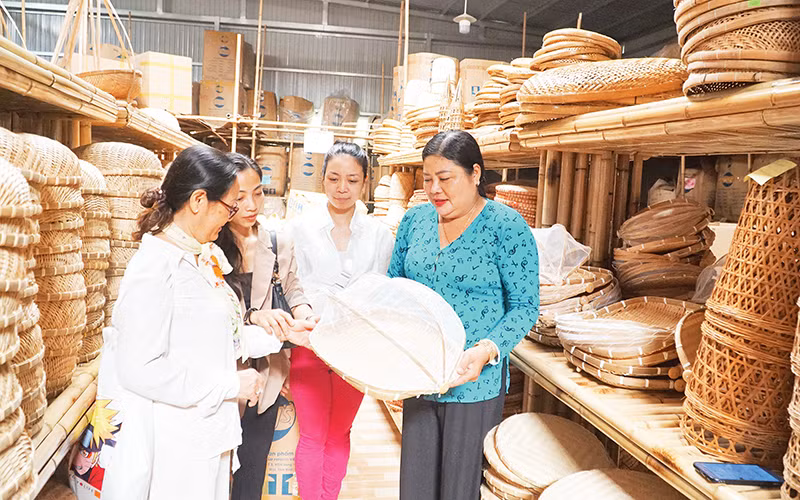 Nghệ nhân Trương Thị Bạch Thủy (bên phải) giới thiệu với du khách tham quan tại phòng trưng bày sản phẩm của Hợp tác xã Mây tre đan Thủy Tuyết.