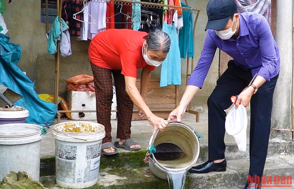 Cán bộ y tế ở Quảng Bình hướng dẫn người dân xử lý dụng cụ chứa nước để diệt loăng quăng.
