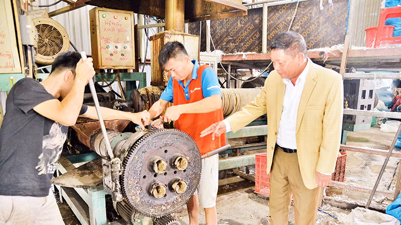 Ông Trần Thanh Văn (phải) hướng dẫn công nhân sửa chữa một số thiết bị, máy móc xây dựng.