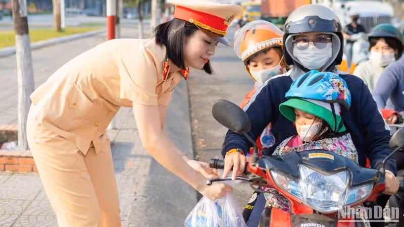 Cán bộ, chiến sĩ Phòng Cảnh sát giao thông Công an tỉnh Đồng Nai phát nước suối, khăn lạnh hỗ trợ người dân về quê đón Tết trên Quốc lộ 1A.