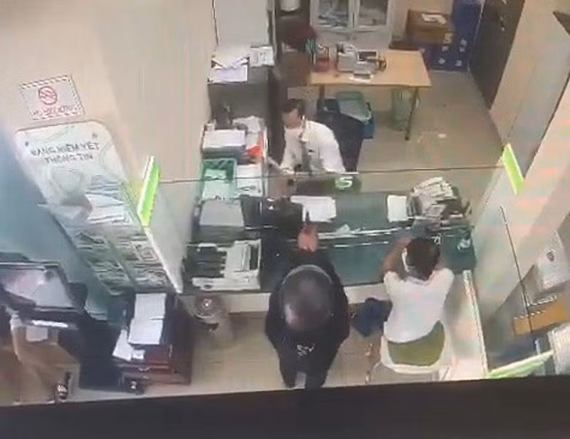 Đối tượng giơ súng uy hiếp nhân viên phòng giao dịch. (Ảnh cắt từ clip) Đối tượng giơ súng uy hiếp nhân viên phòng giao dịch. (Ảnh cắt từ clip)