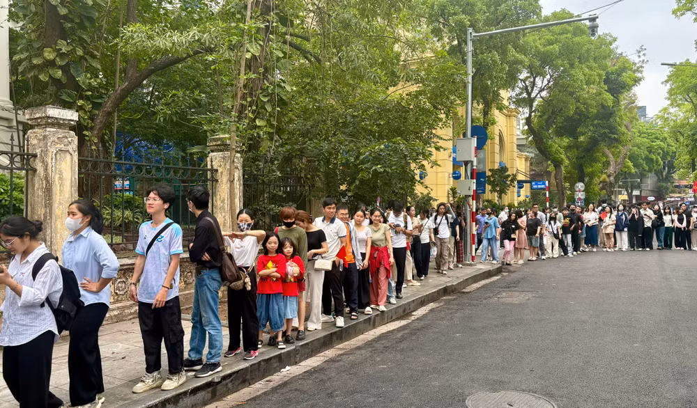 Sáng 27/4, hai chị em Linh Chi và An Nhiên (mặc áo cờ đỏ sao vàng) xếp hàng chờ đến lượt trải nghiệm các sản phẩm báo chí của Báo Nhân Dân.