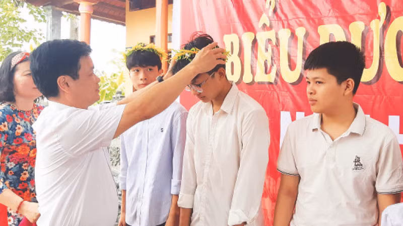 Bí thư Đảng ủy xã Quảng Khê Lê Thanh Tuyên trao vòng nguyệt quế, biểu tượng về thành tích học tập cho học sinh dòng họ Lê.