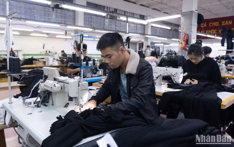 Đặng Thị Trang (áo đen ngồi sau) đang làm việc trong xưởng.