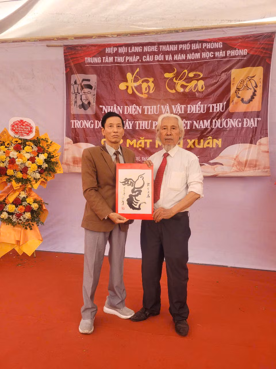 Nhà thư pháp Lê Thiên Lý (phải) tặng bức thư pháp viết theo lối “Vật điểu thư”. Nhà thư pháp Lê Thiên Lý (phải) tặng bức thư pháp viết theo lối “Vật điểu thư”.