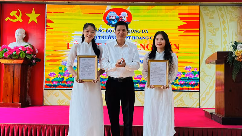 Phó Bí thư Thường trực Quận ủy Đống Đa Nguyễn Anh Cường trao quyết định kết nạp đảng viên cho hai học sinh ưu tú Trường THPT Hoàng Cầu.