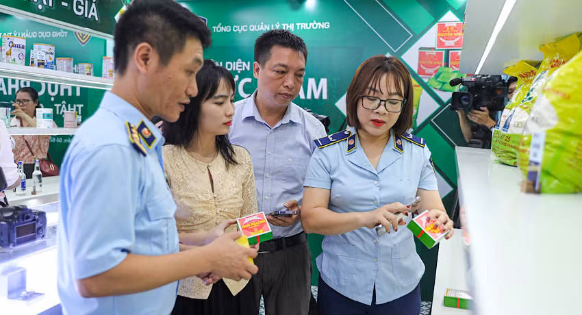 Chuyên viên của Tổng cục Quản lý thị trường hướng dẫn khách tham quan nhận diện bánh cốm Nguyên Ninh thật - giả. (Ảnh: NAM NGUYỄN)