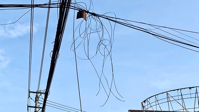 Rất nhiều dây cáp viễn thông bị đứt thòng xuống gần sát đường đi của người dân.