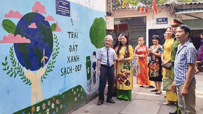 Ông Nguyễn Hữu Bằng (bên trái) cùng người dân Khu dân cư số 3 bên công trình tranh bích họa, làm đẹp diện mạo khu phố.