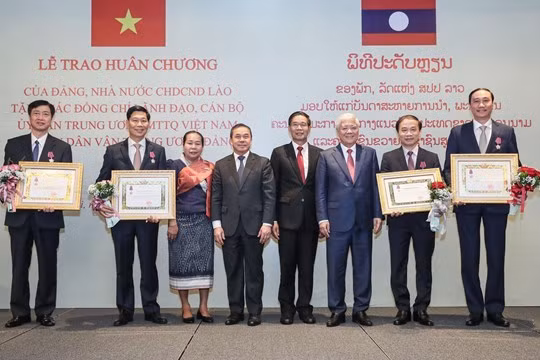 Chủ tịch Ủy ban Trung ương Mặt trận Lào xây dựng đất nước Sinlavong Khoutphaythoune và Chủ tịch Ủy ban Trung ương MTTQ Việt Nam Đỗ Văn Chiến chụp ảnh lưu niệm với các cá nhân được nhận Huân chương Ít-xa-la hạng II, III 