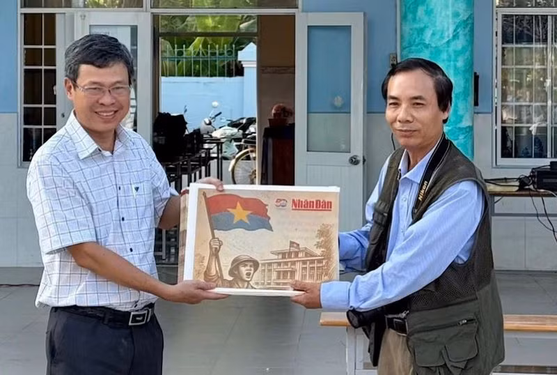 Nhà báo Trọng Duy, đại diện Văn phòng Báo Nhân Dân tại Bạc Liêu trao Phụ san đặc biệt của Báo Nhân Dân đến thầy giáo Dương Bình, Bí thư Chi bộ, Hiệu trưởng Trường Trung học phổ thông Chuyên Bạc Liêu.