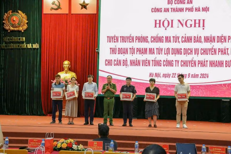 Phó Giám đốc Công an thành phố Hà Nội Nguyễn Thanh Tùng trao ấn phẩm tuyên truyền phòng chống ma túy cho đại diện các công ty chuyển phát nhanh bưu điện EMS.