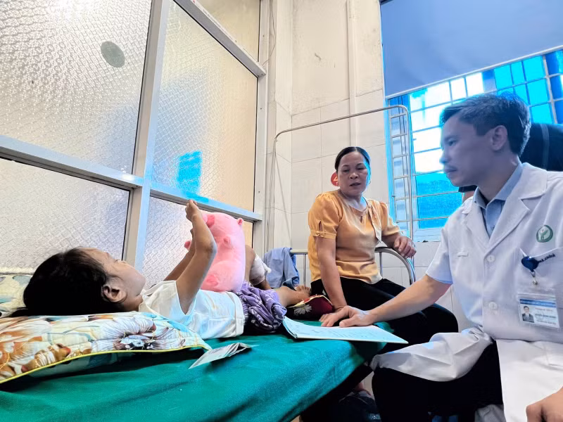 Phó Giáo sư, Tiến sĩ Nguyễn Mạnh Khánh thăm hỏi em bé là nạn nhân trong vụ sạt lở đất. Em đang được bà ngoại chăm sóc tại Bệnh viện đa khoa huyện Bảo Yên.