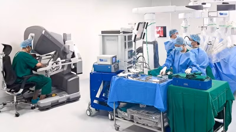 Phó Giáo sư, Tiến sĩ Vũ Lê Chuyên (trái) đang ngồi ở buồng điều khiển robot Da Vinci Xi để phẫu thuật cho người bệnh.