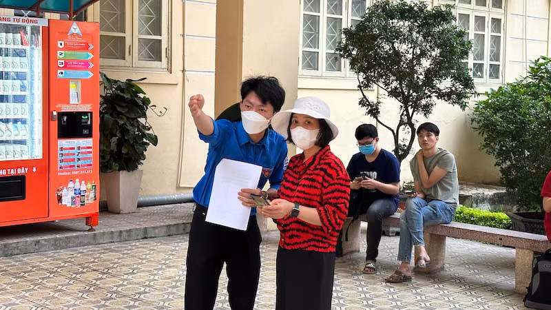 Sinh viên tình nguyện hướng dẫn phụ huynh di chuyển đến phòng chờ thí sinh. (Ảnh: THÚY QUỲNH)