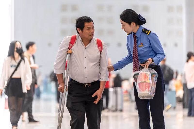 Nhân viên đường sắt hỗ trợ người đi tàu tại ga Kim Hoa, Chiết Giang. Để đáp ứng nhu cầu, ngành đường sắt Trung Quốc đã vận hành hơn 12.000 chuyến tàu mỗi ngày và tăng cường tàu giường nằm cao tốc vào giờ cao điểm.