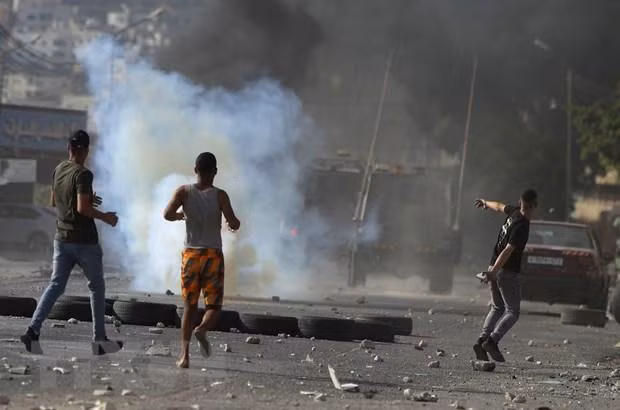 Người biểu tình Palestine ném đá trong cuộc xung đột với binh sĩ Israel tại thành phố Nablus, khu Bờ Tây, ngày 17/8/2022. (Ảnh: AFP/TTXVN)