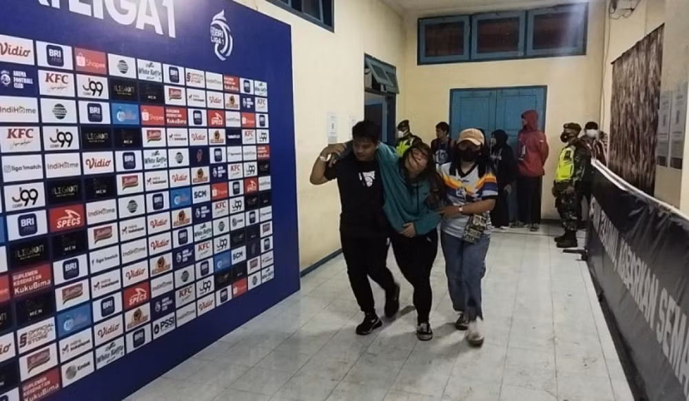 Một nữ cổ động viên được hỗ trợ đưa đi cấp cứu. (Ảnh: Kompas)