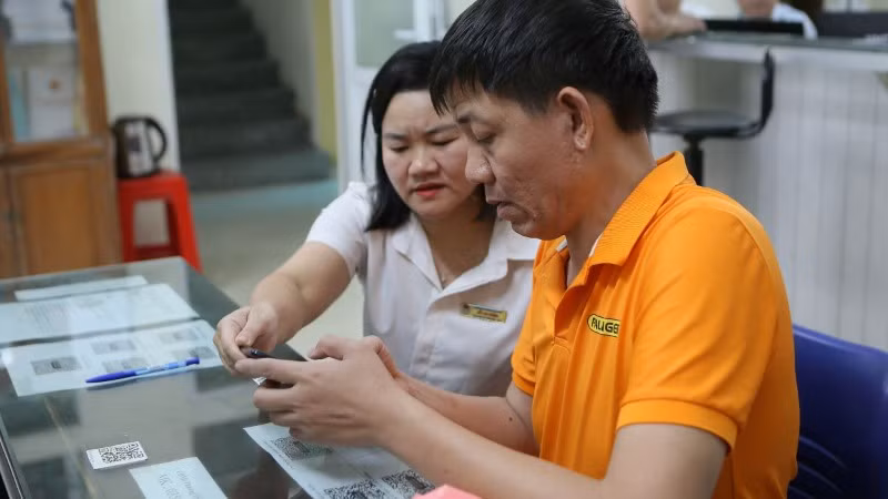 Cán bộ phường hướng dẫn người dân giải quyết thủ tục hành chính thông qua cổng dịch vụ công. (Ảnh minh họa: TTXVN)