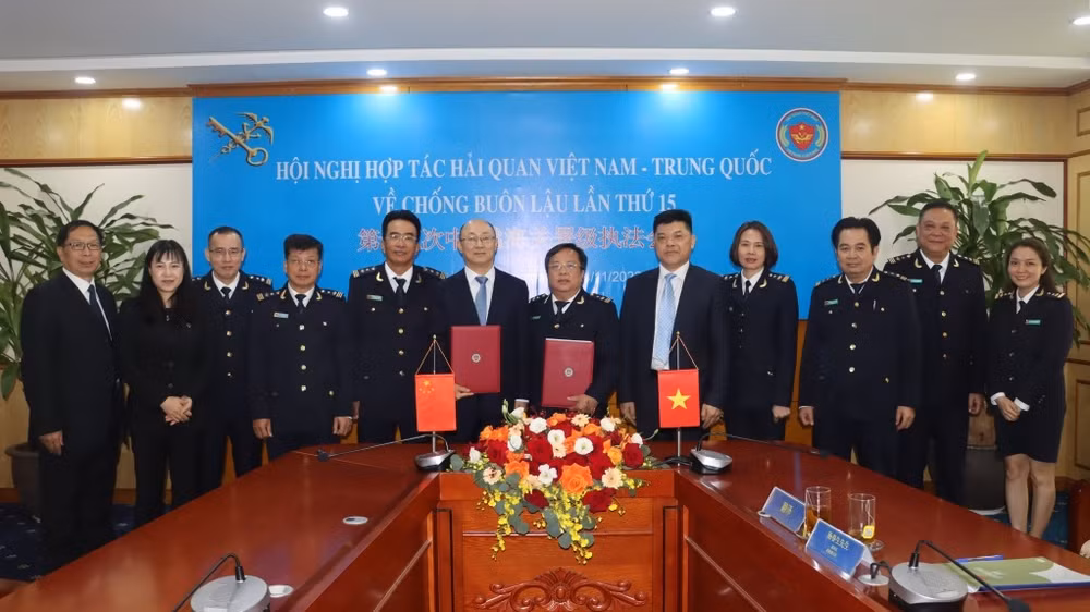 Đại biểu hải quan hai nước trao đổi biên bản ký kết tại hội nghị. (Ảnh: T.Bình) 